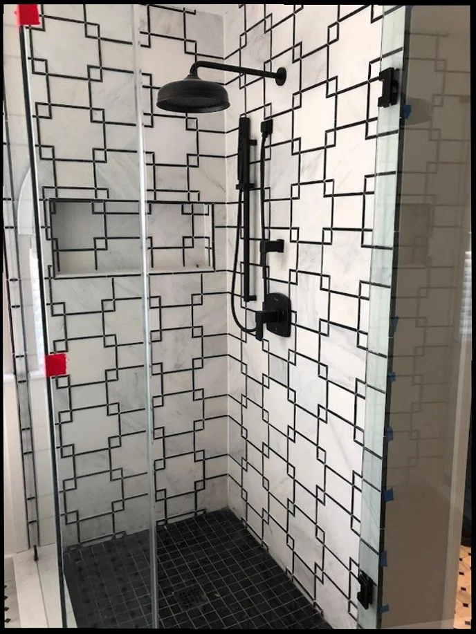 Designer black and white tile shower with matte black fixtures installed by Sandy Springs Plumbing