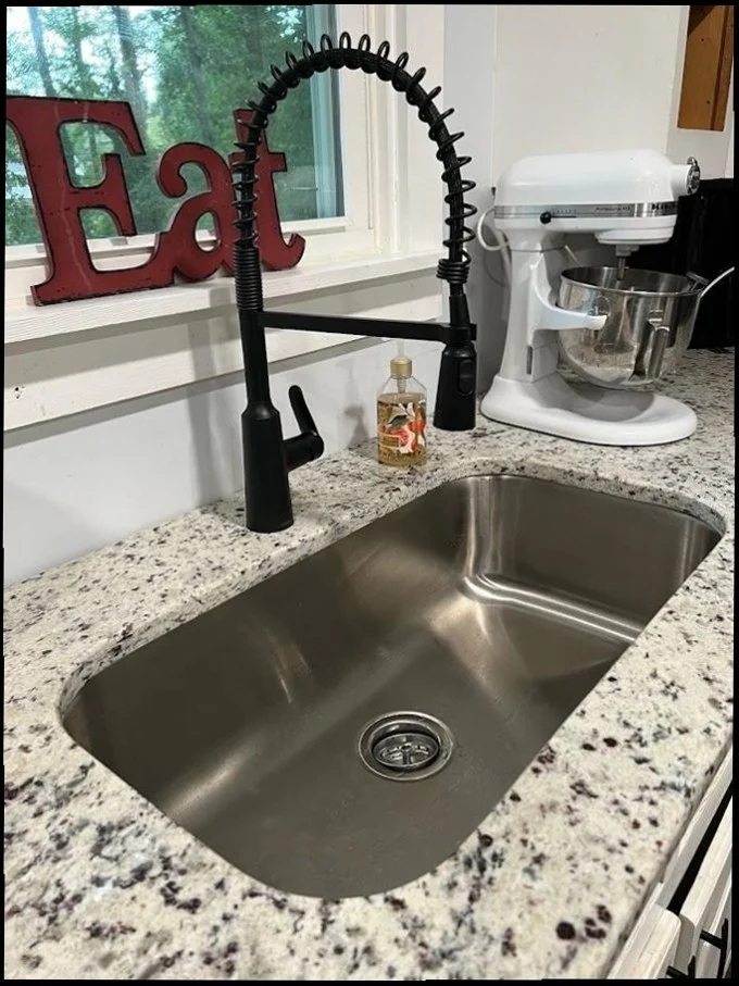 Modern kitchen sink with matte black spring faucet and granite counter by Sandy Springs Plumbing